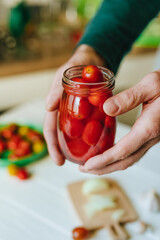 Hands of a person holding pickled cherry tomatoes