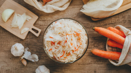 Top view of fresh sauerkraut in a bowl surrounded by ingredients