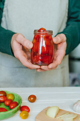Hands of a person holding pickled cherry tomatoes