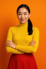 Obraz premium Smiling asian female in bright outfit against orange background