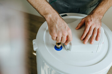 Technician's hands using a screwdriver to repair an electric water heater