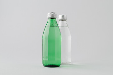 Clear and green glass water bottle mockup on neutral background