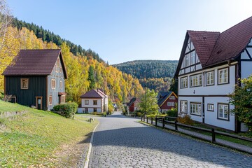 Obraz premium Scenic Autumn View of Charming Cottages with Colorful Trees and Cobblestone Path in Serene Countryside