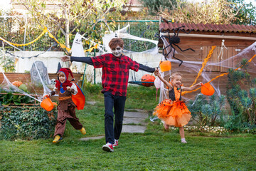 Children race toward camera past Halloween decor in backyard