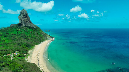 Foto aérea do Morro do Pico em Fernando de Noronha, imponente formação rochosa que domina a ilha, cercada por mar cristalino e vegetação tropical © RNL Fotografia