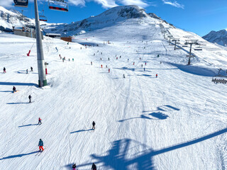 Aerial view of multiple skiers descending sunlit wide slope