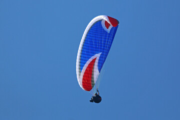 Paraglider flying in a blue sky	