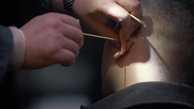 Detailed slow motion of fine brush and wire tool used in traditional ear cleaning by street specialist in Chengdu