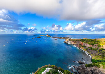 Obraz premium Baía de Santo Antônio em Fernando de Noronha, com águas calmas e azul-turquesa, rodeada por vegetação e morros, cenário paradisíaco do arquipélago