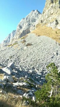 Panorama from the valley of Buni i Jezerces, Prokletije: scenic mountain ridges, rocky slopes and a tourist walking in the distance. Hiking and ecotourism in Albania. Adventure travel concept