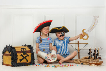 Two kids explore pirate adventures with map, sword and chest