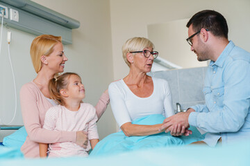 Obraz premium Multi-generational Family Gathering Around Hospital Bed Supporting Senior Woman During Medical Recovery