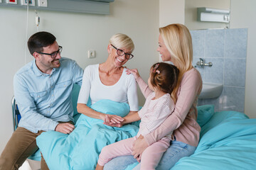 Obraz premium Joyful Family Reunion with Grandmother in a Bright and Cheerful Hospital Room