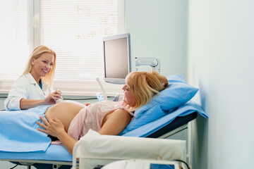 Obraz premium Pregnant Woman Undergoing Ultrasound in Bright Hospital Room with Caring Female Doctor