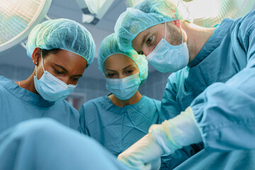 Diverse Group Of Surgeons And Medical Professionals Collaborating During Surgical Procedure In...