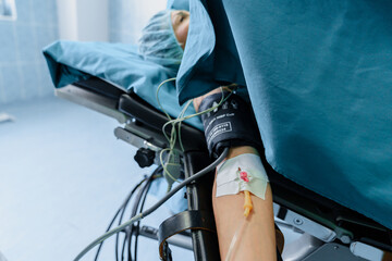 Patient's Arm with IV and Blood Pressure Monitor in a Bright Surgical Room