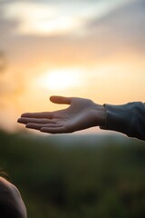 Open hand reaching out against sunset background, symbolizing hope and connection.