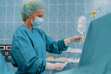 Female Surgeon in Blue Scrubs Preparing IV Drip in Well-Lit Operating Room