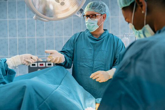 Medical Team in Surgical Attire Operating Under Bright Lights in a Sterile Environment