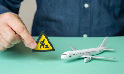 A man holds a construction or repair symbol near a passenger plane. Technical inspection. Aviation...