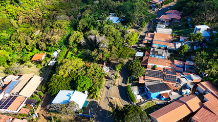 Fototapeta premium Vista aérea da Vila dos Remédios em Noronha, mostrando casas coloridas, ruas estreitas e vegetação tropical. Cenário perfeito para turismo cultural, fotografia urbana e apreciação da história da ilha