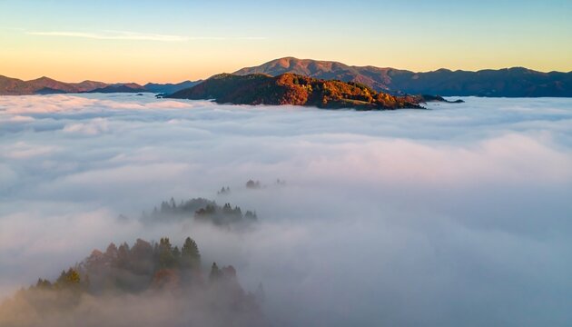 Panoramic aerial view of autumn mountains rising above a thick blanket of morning fog at sunrise.