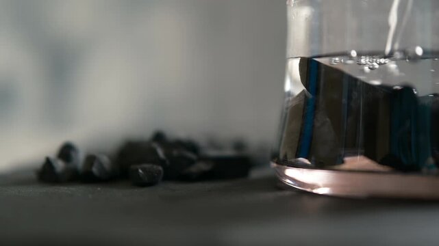 glass with shungite stones, A pile of shungite on a black background. a jar of water  shungite is used for water. water purification alternative medicine