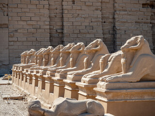 The entrance of Karnak Temple, featuring rows of ram-headed sphinx statues lining the Avenue of Sphinxes, leading to the ancient temple complex