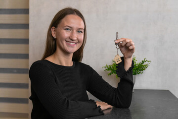 Happy homeowner showing keys to her new house, real estate purchase and investment concept, smiling...