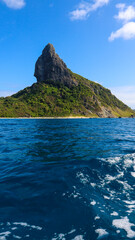 Morro do Pico em Fernando de Noronha, formação rochosa icônica cercada por mar azul e vegetação tropical, cartão-postal do arquipélago