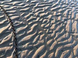 Textured beach sand with a metal chain tidal ripples texture background
