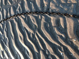 Textured beach sand with a metal chain tidal ripples texture background