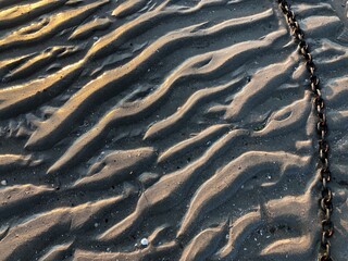 Textured beach sand with a metal chain tidal ripples texture background