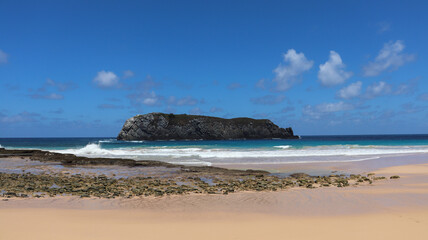 Grande rocha da Ilha do Leão em Noronha cercada pelo mar azul e falésias, marcando paisagem natural preservada da região