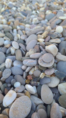 A close-up view of various smooth pebbles and stones in different shades of gray, brown, and white. The texture and shapes of the stones are clearly visible.
