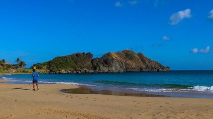 Turista correndo na Praia do Meio em Fernando de Noronha, aproveitando areia clara, mar cristalino e a natureza preservada do paraíso nordestino brasileiro