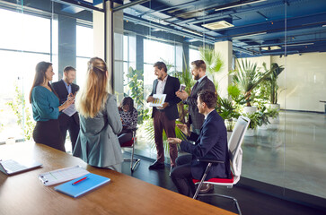 Businessman conducts a meeting or presentation for a team of office staff. Group of colleagues engaged in a work related conversation, discussing business matters to enhance collaboration.
