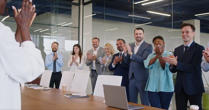 Young multicultural team giving a standing ovation in the boardroom. A female boss commands her subordinates in a meeting room. Happy business people greeting the company owner