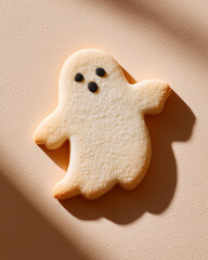 Halloween ghost cookies on beige background. Cute spooky gingerbread biscuits shaped like ghosts, isolated on ivory backdrop. Festive holiday dessert illustration.