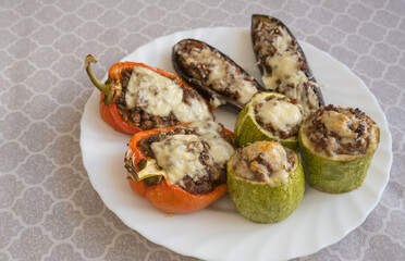Baked eggplants, zucchini and peppers stuffed with minced meat and cheese on one plate.