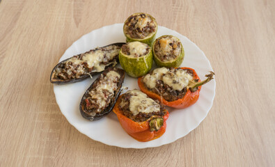 Baked eggplants, zucchini and peppers stuffed with minced meat and cheese on one plate.