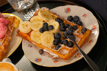 Belgian waffle with banana and blueberries on floral plate