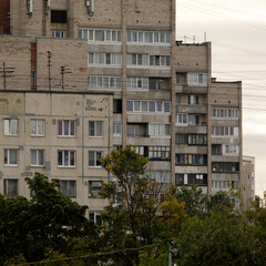Aging Soviet-style residential building with beige brick and concrete facade, grid windows,...