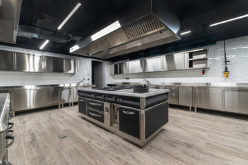 A fully equipped commercial kitchen features stainless steel appliances, a large central cooking area, and an organized workspace ideal for professional chefs during busy hours