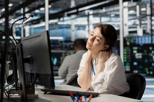 Exhausted server farm IT expert having stiff neck after looking at computer screen for too long. Tired system administrator in data center stressed by long hardware troubleshooting session - Powered by Adobe