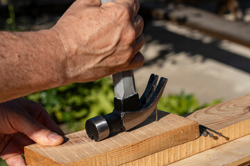 A worker using a hammer nail puller to pull a nail out of a wooden board, closeup. Hand tool for working. Multifunction shockproof steel hammer and nail