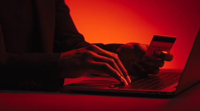 Persona di colore digita sulla tastiera il codice della carta di credito per un pagamento online; e-commerce, sicurezza informatica e protezione dei dati finanziari, pagamento