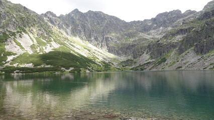 Zbiornik wodny w górach z widocznym zielonym zboczem góry © tomo81