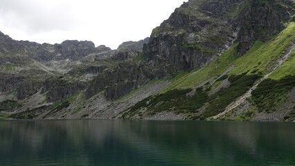 Zbiornik wodny w górach z widocznym zielonym zboczem góry © tomo81