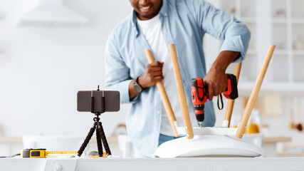 Handyman blogger shooting video instructions for assembling furniture at home with own hands, using...